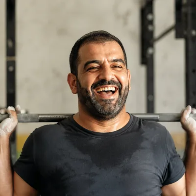 Ein Mann in den Dreißigern legt im Fitnessstudio eine Langhantel ab, Magnesia an den Händen